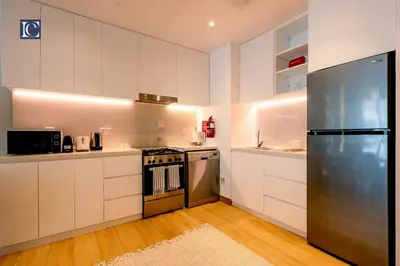 a kitchen with white cabinets and a stainless steel refrigerator at Luxury Escapes - Breathtaking 1BR with Sea View Port Lamer in Dubai