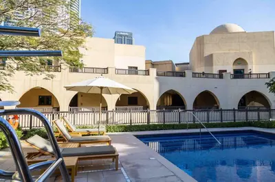 a pool with chairs and an umbrella next to a building at Upgraded 2bdr with acess to Dubai Mall in Dubai