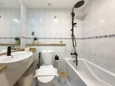 a bathroom with a toilet and a sink and a bath tub at Stylish Lakefront Studio with King Bed and Balcony in Dubai