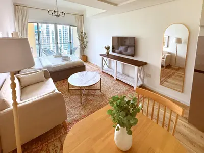 a living room with a couch and a table at Stylish Lakefront Studio with King Bed and Balcony in Dubai