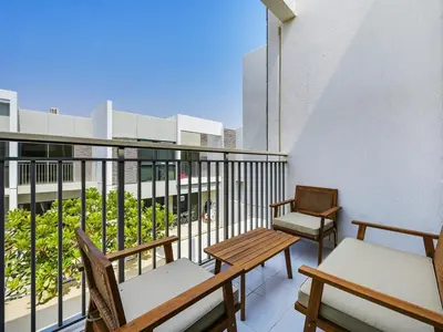 a balcony with two chairs and tables on a building at 4BR Luxurious Villa DAMAC Hills 2 in Dubai