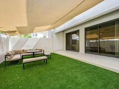 a patio with two benches and green grass at 4BR Luxurious Villa DAMAC Hills 2 in Dubai