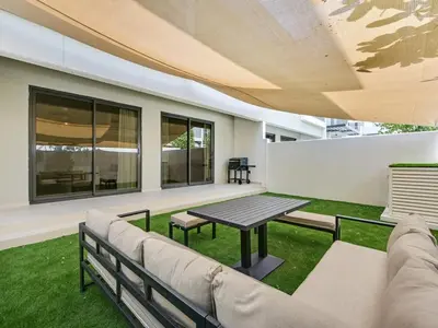 a patio with a couch and a table and some grass at 4BR Luxurious Villa DAMAC Hills 2 in Dubai