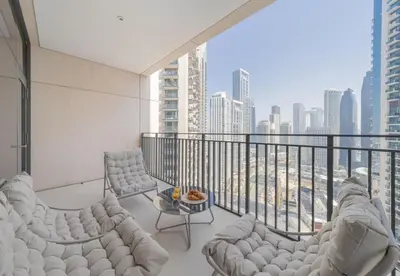 a balcony with white furniture and a view of the city at Luxury 3BR Downtown Stay Near Burj in Dubai