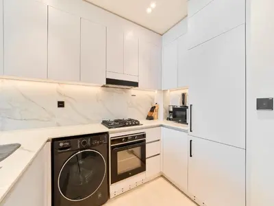 a kitchen with white cabinets and a black dishwasher at FAM Living Minimalist 1BR Gem in Binghatti Amber in Dubai