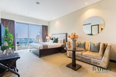 a bedroom with a bed and a couch and a mirror at The Classy in Dubai