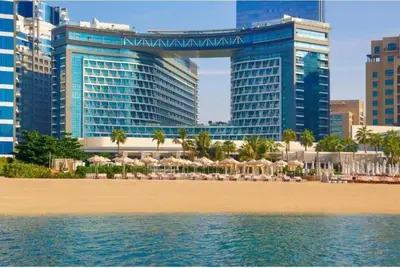 a beach with umbrellas in front of some buildings at Seven Palm Jumeirah Studio in Dubai