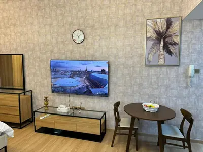 a living room with a table and a clock on the wall at Champion Tower 1 Sports city By Al sarya Holiday Homes in Dubai