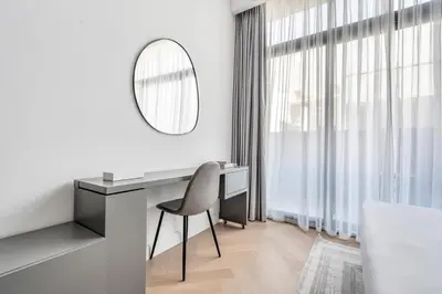 a white room with a desk and a mirror at DAYF-SER03 Brand New Studio with Balcony in JVC in Dubai