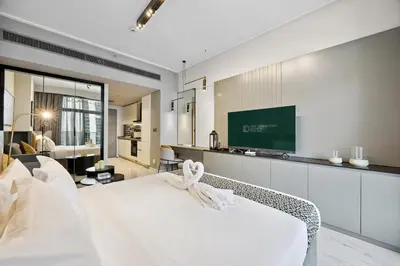 a bedroom with a white bed and a flat screen tv at Luxury Escapes Modern Studio MAG 318 in Dubai