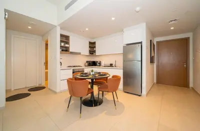 a kitchen with a table and chairs and a refrigerator at Zapbed House -Stylish 1 BR Apartment Downtown Views II Tower 2 in Dubai