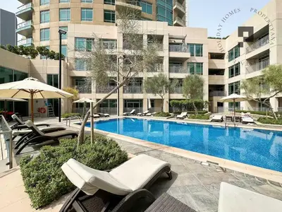 a swimming pool with chairs and umbrellas next to a building at Cozy 1BR in Burj Views I Top Location Walk to Dubai Mall & Burj Khalifa I Wi-Fi in Dubai