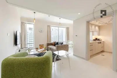 a living room with a green couch and a table at Cozy 1BR in Burj Views I Top Location Walk to Dubai Mall & Burj Khalifa I Wi-Fi in Dubai