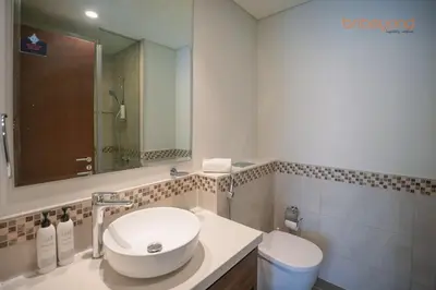 a bathroom with a sink and a toilet and a mirror at Bnbeyond's Canal Dreams and Luxe 2BR in Dubai