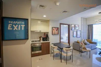 a kitchen and a living room with a table and chairs at Bnbeyond's Canal Dreams and Luxe 2BR in Dubai