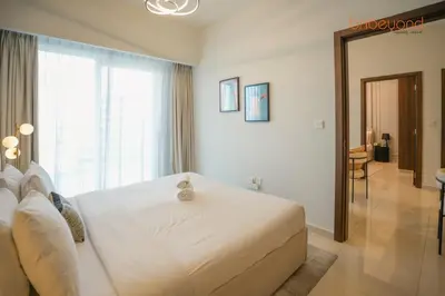 a bedroom with a large white bed with a window at Bnbeyond's Canal Dreams and Luxe 2BR in Dubai
