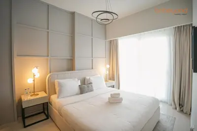 a bedroom with a white bed and a window at Bnbeyond's Canal Dreams and Luxe 2BR in Dubai