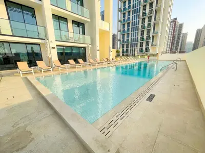 a large swimming pool in a building with chairs at Brand New Studio In Tulip JVC in Dubai