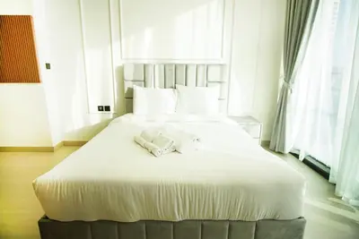 a large white bed with two towels on it at Brand New Studio In Tulip JVC in Dubai