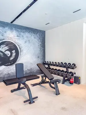 a gym with several treadmills and a wall with a painting at SuperHost- Modern Studio in Arjan with pool & Gym in Dubai