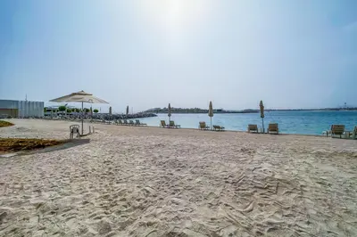 a beach with chairs and an umbrella and the water at Sea View 2BR Apartment in Beach Vista 2 in Dubai