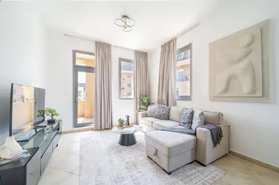 a living room with a couch and a tv at Cozy 1BR in the Peaceful Community of Motor City in Dubai