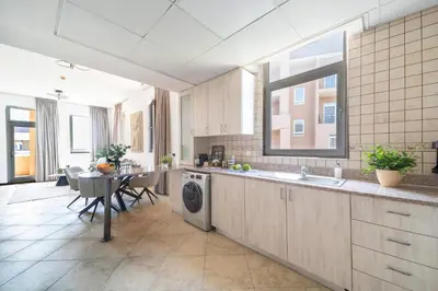 a kitchen with a washing machine and a table with chairs at Cozy 1BR in the Peaceful Community of Motor City in Dubai