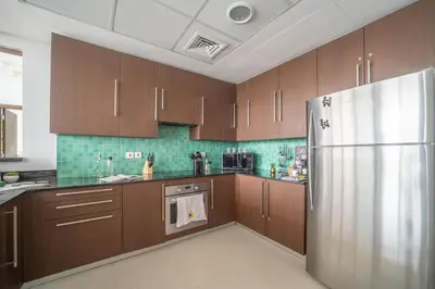 a kitchen with wooden cabinets and a stainless steel refrigerator at Lavish 2BR - Study with Spacious Balcony in DIFC in Dubai