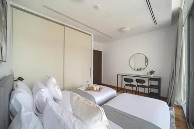 a bedroom with two beds and a table and a mirror at Lavish 2BR - Study with Spacious Balcony in DIFC in Dubai