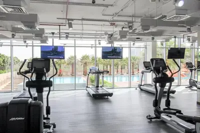 a gym with cardio machines and a swimming pool at Lavish 2BR - Study with Spacious Balcony in DIFC in Dubai