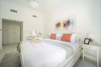 a white bedroom with two beds and a table at Frank Porter - Zaafaran 4, Old town, Downtown Dubai in Dubai
