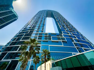 a tall blue building with palm trees in front of it at ADDRESS BEACH RESORT Residence Million Dollar Sea and Palm View DXB AIRPORT VIP Shuttle option in Dubai