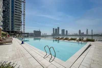 a large swimming pool with chairs and a city skyline at Brand New Stylish 1-Bed Getaway with Private Beach and Palm Views in Dubai