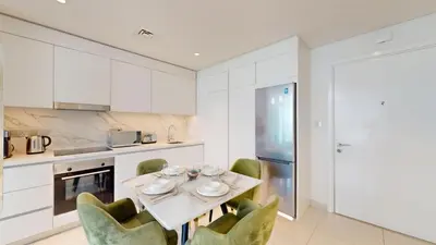 a kitchen with a table and green chairs at Vacationer I Luxurious 1 Bedroom Apartment I Private Beach and Infinity Pool Access in Dubai