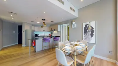 a dining room and kitchen with a glass table and chairs at Vacationer I Steps to Metro I Premium 2 Bedroom Apartment I Yacht Bay Marina in Dubai