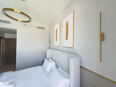 a bedroom with a bed with white sheets and paintings at GRANDE SIGNATURE with a direct Burj Khalifa view and Private Fountain Show with DXB AIRPORT VIP Shuttle option for 6 guests in Dubai