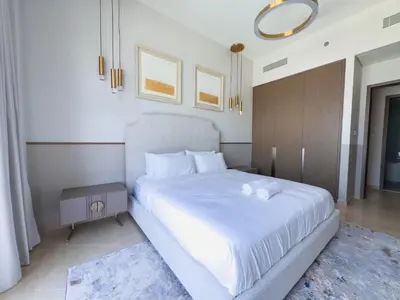a bedroom with a large bed with white sheets at GRANDE SIGNATURE with a direct Burj Khalifa view and Private Fountain Show with DXB AIRPORT VIP Shuttle option for 6 guests in Dubai