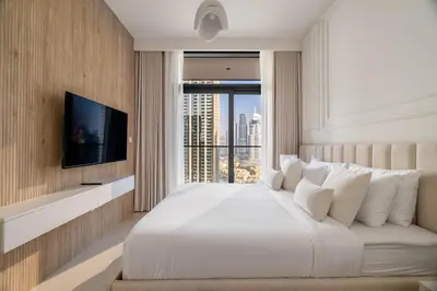a bedroom with a large white bed and a television at Luxurious 4BR with Boulevard View - 10 min to Burj & Mall in Dubai
