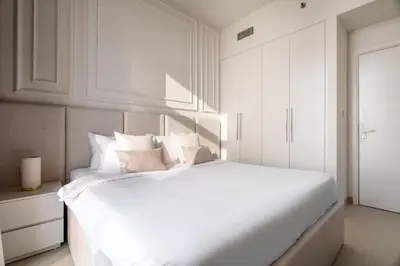 a white bedroom with a large white bed with pillows at Luxurious 4BR with Boulevard View - 10 min to Burj & Mall in Dubai