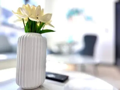 a white vase with flowers in it on a table at Luxury Apartment Burj Khalifa View Summer Offer in Dubai