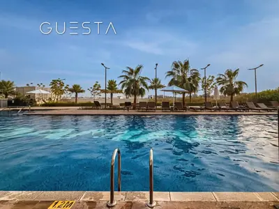 a large swimming pool with chairs and palm trees at Damac Hills - Artecia Tower, Dubai in Dubai