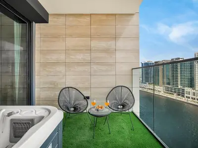 a balcony with two chairs and a table with drinks at Premium Studio Private Jacuzzi Canal View in Dubai