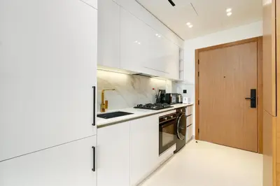 a kitchen with white cabinets and a wooden door at Ahlan HH - Brand New Summer Suite, Near Circle Mall in Dubai