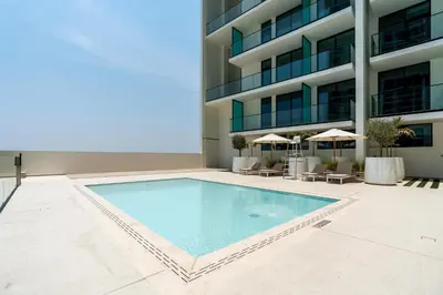 a swimming pool in front of a building at Ahlan HH - Brand New Summer Suite, Near Circle Mall in Dubai