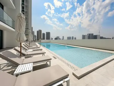 a pool on the roof of a building with lounge chairs at Feel at Home Stylish 1BR in Binghatti Tulip Dubai in Dubai