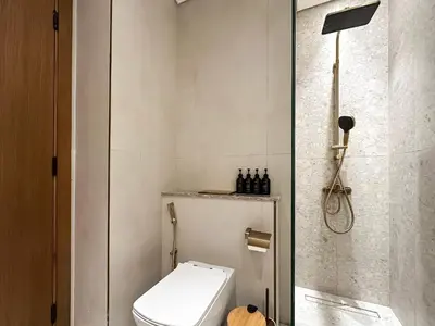 a white bathroom with a toilet and a shower at Feel at Home Stylish 1BR in Binghatti Tulip Dubai in Dubai
