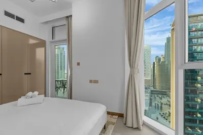 a bedroom with a white bed and a large window at Modern apartment in a prime location in Dubai! in Dubai