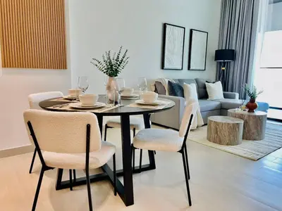 a dining room table and chairs in a living room at Modern 1br In Jvc Balcony Pool Free Parking in Dubai