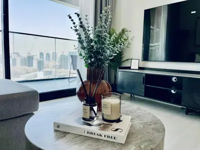 a living room with a table with a candle and a book at Modern 1br In Jvc Balcony Pool Free Parking in Dubai