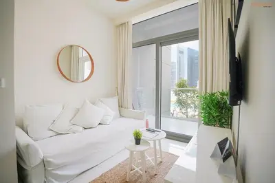 a white living room with a white couch and a window at Bnbeyond's Serene Poolside Bliss in Dubai
